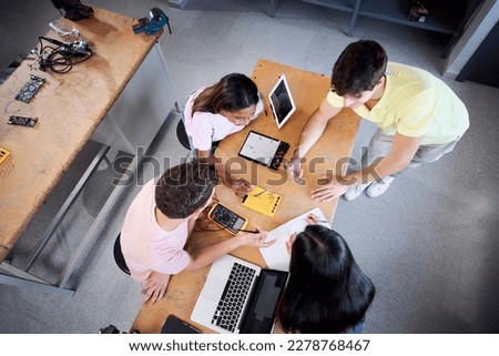 Top view of a Group of students from the technical college using a laptop in technology class. Classmates collaborating on a project in high school - programming at classroom. High quality photo