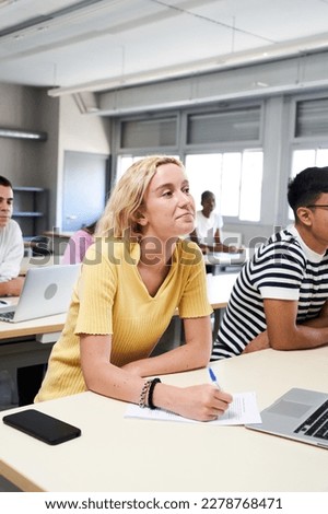 Vertical photo of High school science class: A boy and girl using a laptop computer while attending to the teacher in class. Group of students learning in the classroom. High quality photo