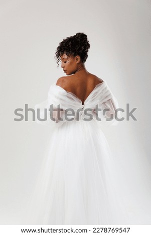 Model with dark skin posing with her back in a white wedding dress. Royalty-Free Stock Photo #2278769547