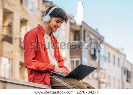 young man on the street with headphones and laptop outdoors Royalty-Free Stock Photo #2278784297
