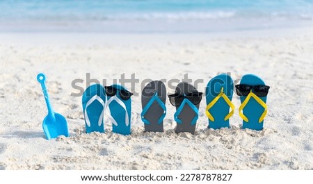 Three pairs of flip flops in sunglasses on the beach on the background of ocean in the Maldives. Family beach holiday concept.  Royalty-Free Stock Photo #2278787827