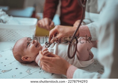 Pediatrician doctor examines newborn with stethoscope. Female doctor examines infant with stethoscope. Soft blur of the doctor hands use stethoscope to check newborn baby Royalty-Free Stock Photo #2278794293