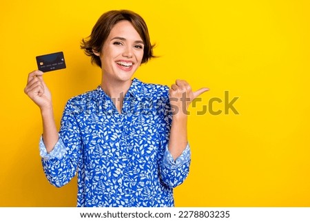 Photo of cheerful adorable lady wear blue stylish clothes hand thumb direct empty space isolated on yellow color background