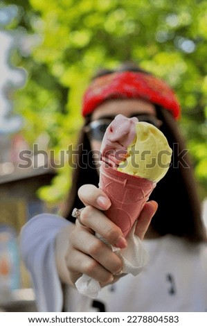Photo of a girl in glasses and a bandana holds a pink ice cream, a diamond ring on her hand