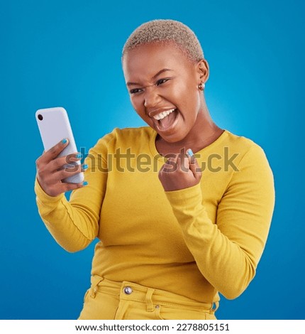Black woman, phone and fist celebration in studio, blue background and winning online prize. Happy female model celebrate mobile promotion, bonus and excited for deal, success and competition winner Royalty-Free Stock Photo #2278805151