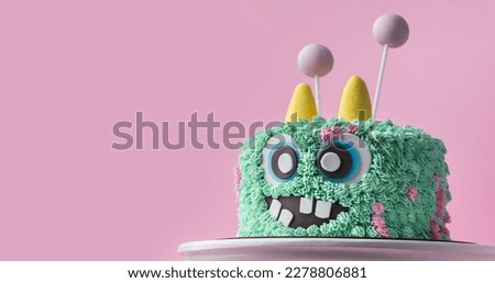 Monster theme cake on the pink background. Funny birthday cake with turquoise fluffy cream cheese frosting. Spooky monster pastry with edible fur. Happy Halloween party