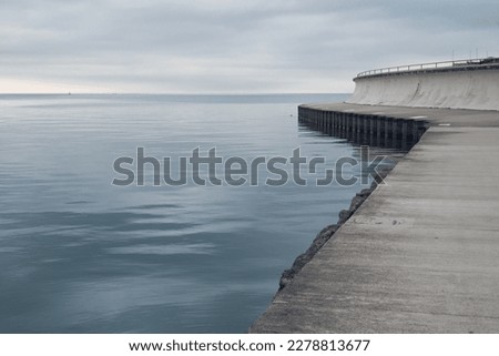 Empty waterfront path on a cloudy day. Peaceful and somber mood. Royalty-Free Stock Photo #2278813677