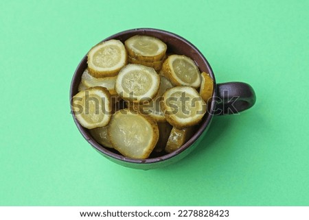 sliced pieces of canned cucumbers in a brown cup on a green table