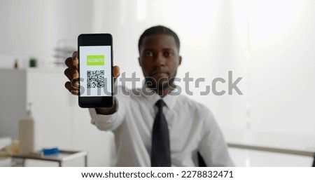 African-American businessman in medical office showing vaccinated qr-code on smartphone at camera. Man get vaccinated for coivd-19 and show electronic certificate Royalty-Free Stock Photo #2278832471