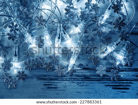 christmas lights decoration with silver snowflakes on wooden background