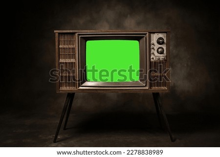 Retro old television with chroma key green screen standing in a dark room, antique and vintage TV style photo.
