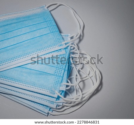 Vertical picture of blue surgical masks stacked in layers on gray background, Bacteria protection concept.