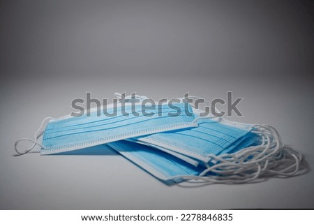 Blue surgical masks with rubber ears straps  stacked in layers on middle gray background, Bacteria protection concept.