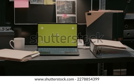 Greenscreen display on portable laptop in incident room, isolated chroma key template. Wireless computer placed on desk showing blank copyspace mockup screen, evidence board map. Royalty-Free Stock Photo #2278854399