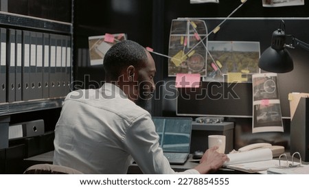 Private investigator conducted research to solve case, analyzing criminal information to catch suspect. Male law agent using laptop and folder files to uncover clues and crime details. Royalty-Free Stock Photo #2278854555