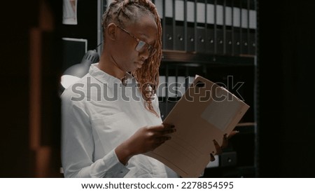 Private investigator analyzing gathered information in police agency office. Woman detective sitting in evidence room and reading archive records, studying clues and case files.