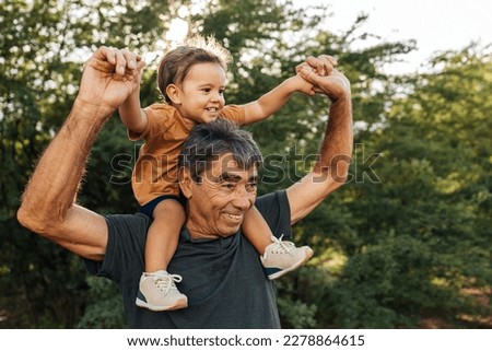 Playful grandfather spending time with his grandson in park on sunny day Royalty-Free Stock Photo #2278864615