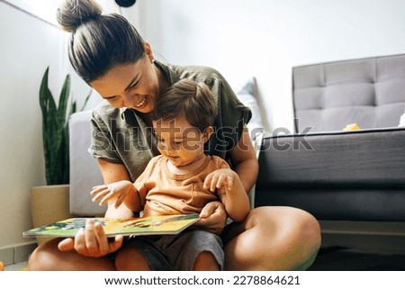 Mom reading a book with baby boy at home. Early age children education, development. Mother and child spending time together. Candid lifestyle. Royalty-Free Stock Photo #2278864621