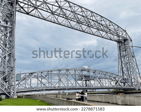 Aerial lift bridge is a major tourist attraction in Duluth MN on cloudy day. Group of tourists having fun together. Royalty-Free Stock Photo #2278871583