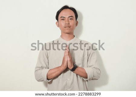 asian man with greeting gesture apologizing. hand gesture greeting symbol of welcome, apologize, greeting. Indonesian man wearing neat and polite shirt on white isolated background