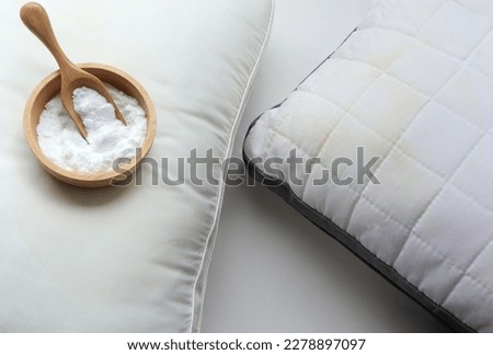 White pillow with yellow saliva stains and baking soda (sodium bicarbonate) on white background. baking soda to clean their dirty mattresses and Home cleaning concept.