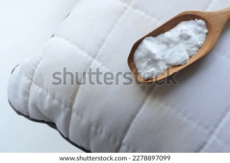 White pillow with yellow saliva stains and baking soda (sodium bicarbonate) on white background. baking soda to clean their dirty mattresses and Home cleaning concept.
