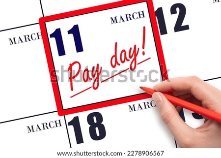 11th day of March. Hand writing text PAY DATE on calendar date March 11 and underline it. Payment due date.  Reminder concept of payment. Spring month, day of the year concept.