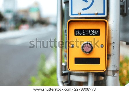 Japanese crosswalk pedestrian push button.Translation: "Please wait"