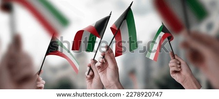 A group of people holding small flags of the Kuwait in their hands. Royalty-Free Stock Photo #2278920747