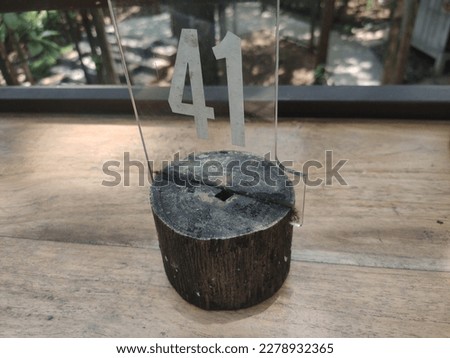 unique table number from carved acrylic number 41, handmade, stuck to a burnt wooden mat Royalty-Free Stock Photo #2278932365