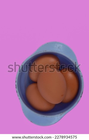 four eggs in a blue container on a pink background