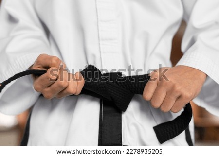 Fighter tightening karate belt against rock crashing down from cliff. sport. Royalty-Free Stock Photo #2278935205