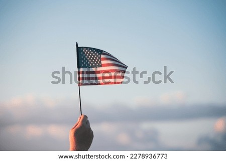 Man holding american USA flag in the sunset. Independence Day or traveling in America concept.