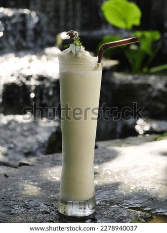 fruit juice, fruit smoothie, fruit juice, fruit juice in glass Placed on a rock near the waterfall.