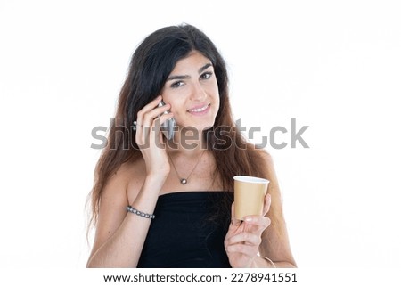 Young brunette woman holding hot cup of coffee speaking on mobile phone on isolated white background