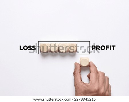 The path to profit in stock exchange. Improving from financial loss to making profit. Business profitability, risk taking. Hand places a wooden cube to the loading bar moving from loss to profit.