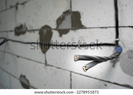 Divorced electrical wires on bare walls made of aerated concrete bricks. Close-up of the prepared wire for the socket on the wall. Electrical planning in a private house during construction Royalty-Free Stock Photo #2278951873