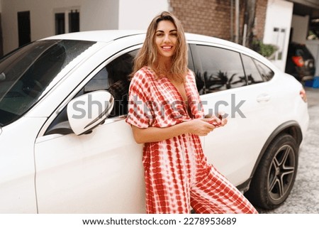 Happy brunette woman  posing near luxury modern white car outdoor. Travel and vacation concept.