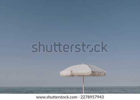Minimal summer holidays vacation concept. Beach umbrella in front of blue sky and sea or ocean