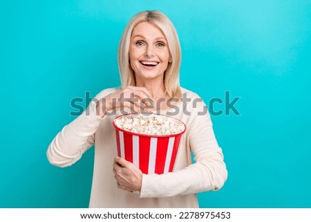 Photo of beautiful retired woman blonde hair wear white shirt hold bucket unhealthy pop corn surprised moment film isolated on cyan color background