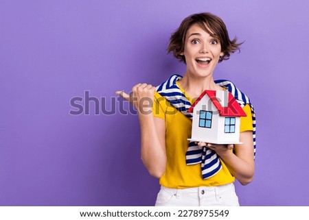 Photo of astonished lady wear trendy striped clothes demonstrate empty space recommend buy apartment isolated on purple color background