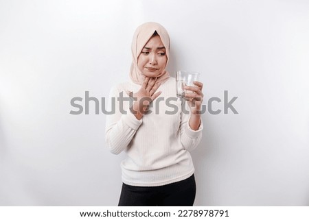 An Asian Muslim woman feels so thirsty because of the hot weather during the summer season while fasting Royalty-Free Stock Photo #2278978791
