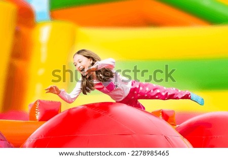 Happy little girl having lots of fun on a inflate castle while jumping. Colorful playground. Royalty-Free Stock Photo #2278985465