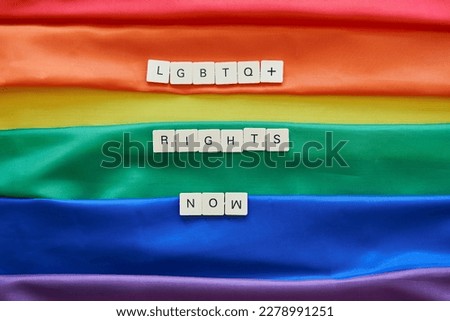 LGBT rights now concept. LGBTQ+ rights now spelled with craft letters over lgbt rainbow flag