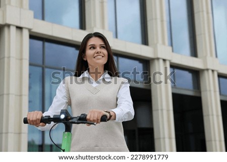 Businesswoman riding electric kick scooter on city street, space for text Royalty-Free Stock Photo #2278991779