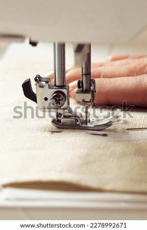 Vertical close up cropped woman hands using sewing machine for repair clothes with thread stitching. Tailor, seamstress handcrafting, sewing stuff. Handmade work, extremely close up of presser foot