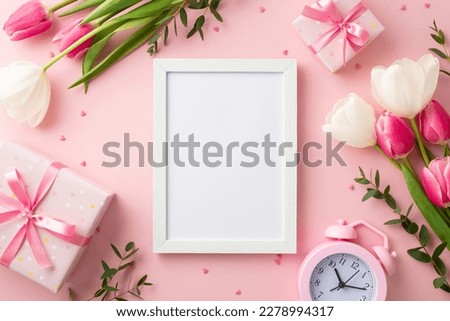Mother's Day concept. Top view photo of photo frame gift boxes with bows bunches of tulips alarm clock and sprinkles on isolated pastel pink background with blank space