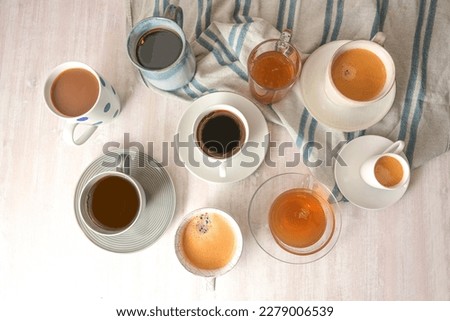 Several different cups and mugs with coffee and tea drinks on a light table with a blue gray towel, high angle view from above, selected focus, narrow depth of field Royalty-Free Stock Photo #2279006539