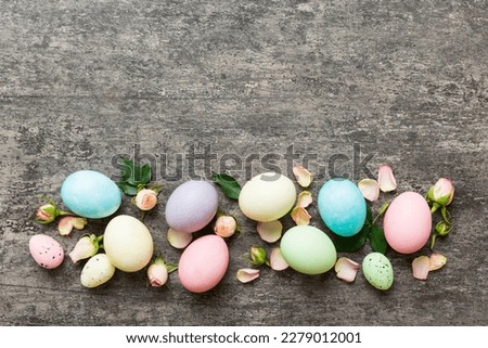 Happy Easter. Easter eggs on colored table with yellow roses. Natural dyed colorful eggs background top view with copy space.