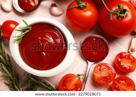 Bowl with tasty ketchup and fresh vegetables on pink tile background, closeup